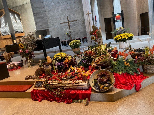 Reich geschmückter Erntedank-Altar in der Kirche Zur Göttlichen Vorsehung mit Obst, Gemüse, Kürbissen, Chrysanthemen und roten Tüchern